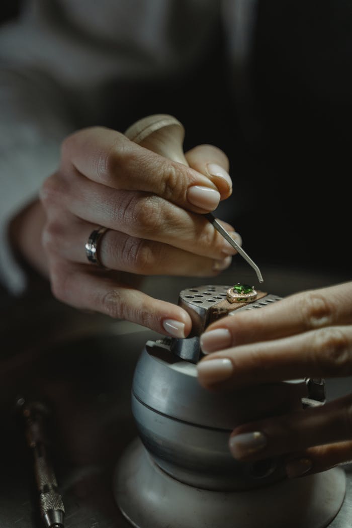 Contact Close-up of a jeweler skillfully crafting an emerald ring, showcasing precision and detail.